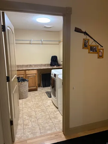 Laundry room featuring tiled flooring, built-in cabinetry, durable countertop, and overhead shelving