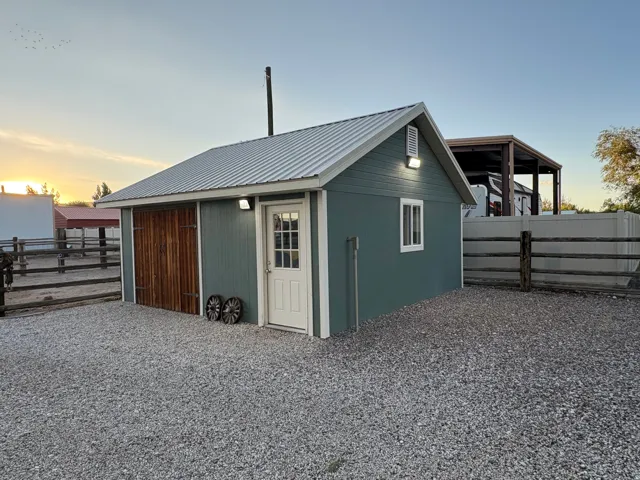 Detached structure featuring a metal roof, blue-green siding, wood-paneled sliding door, and a white entry door with paneled glass