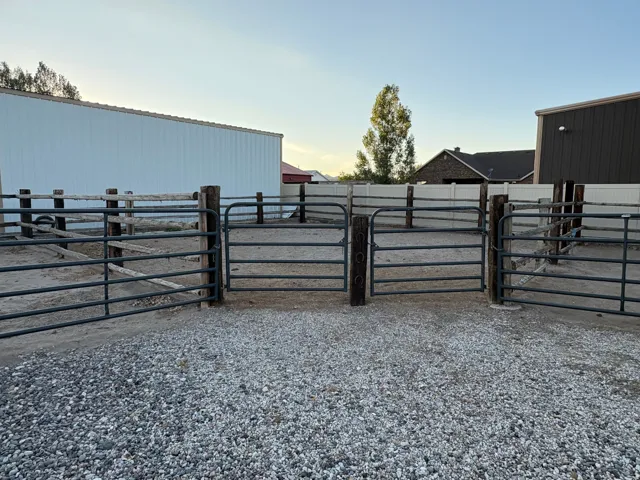 Gravel ground covering, multiple metal gates, and wood fencing