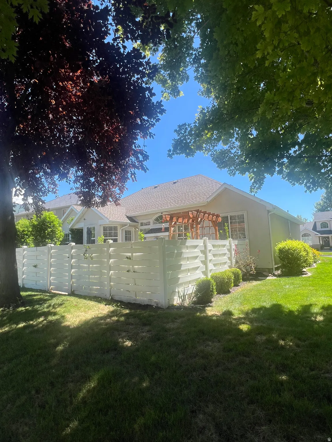 Manicured lawn with a white privacy fence and a wooden pergola