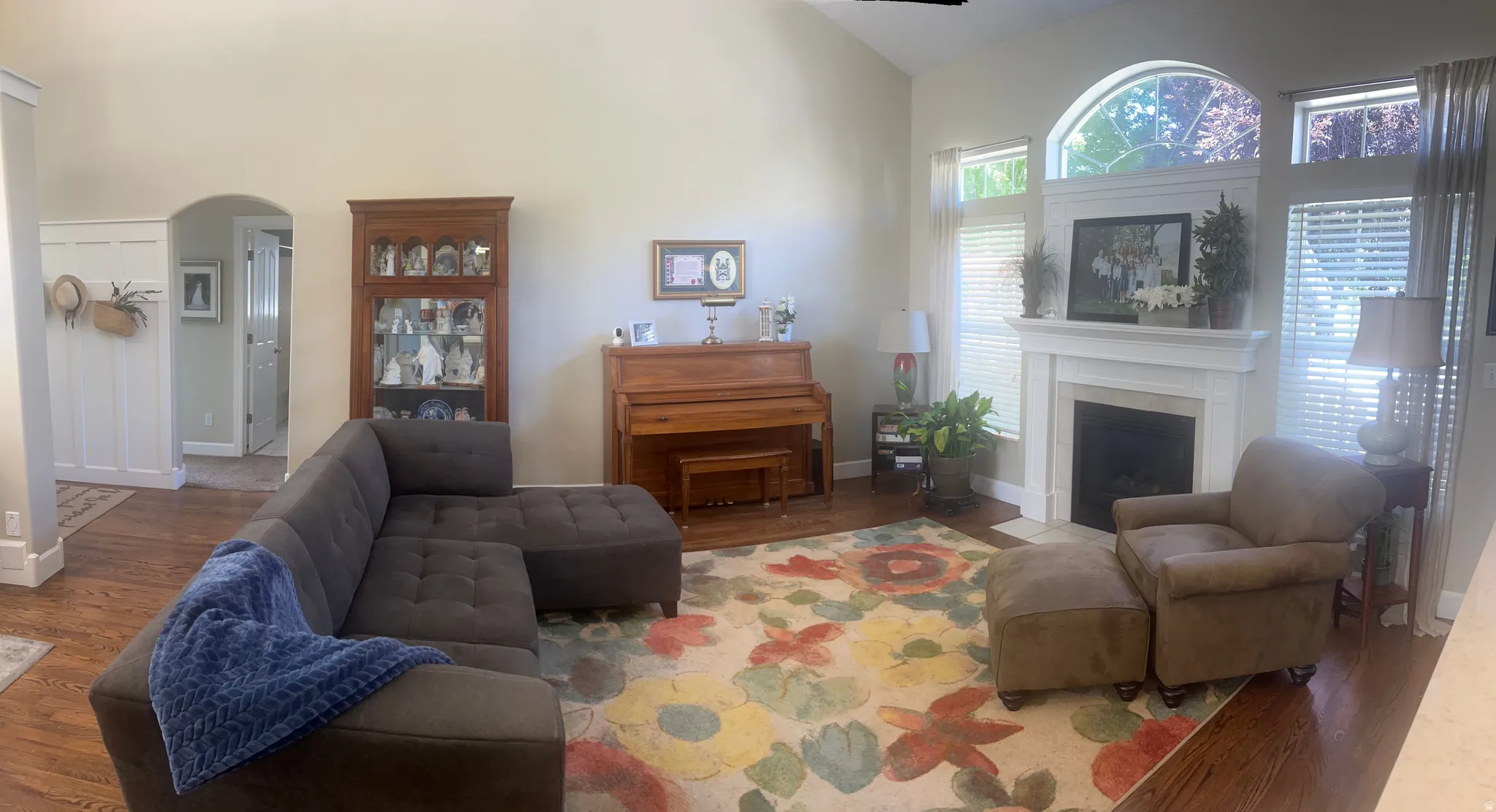 Spacious interior featuring wood-finish flooring, a fireplace with a white mantel, and arched window details