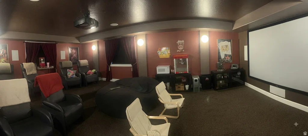 Media room featuring a large projection screen, built-in projector, tiered seating, and wall sconces