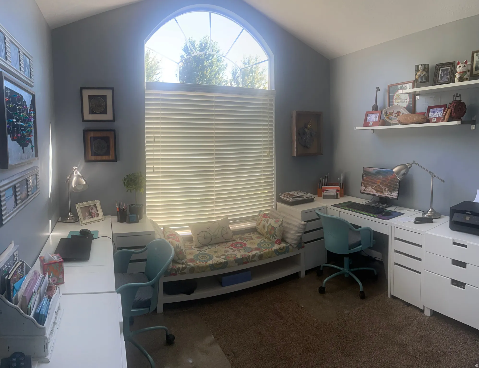 Vaulted ceiling with an arched window, wall-mounted shelving, and carpeted flooring
