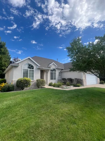 Stucco exterior with stone accenting, arched windows, and a multi-pane garage door