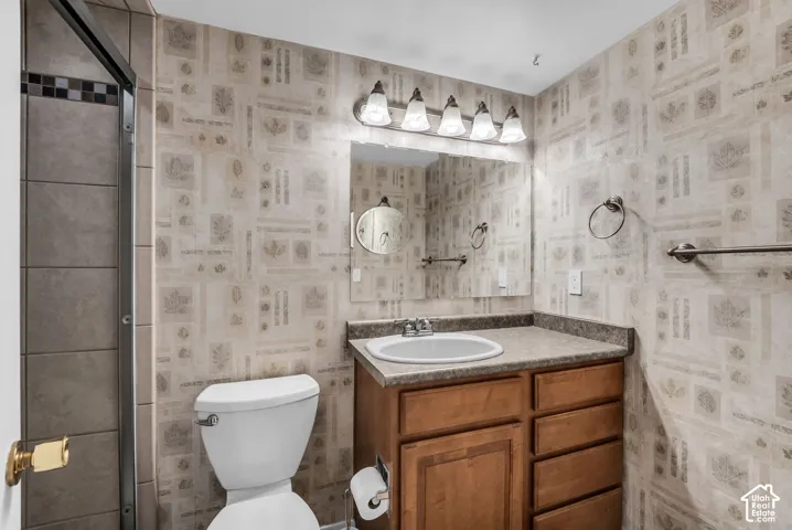 Wood-finish vanity with a drop-in sink, wall-mounted mirror, and light fixture