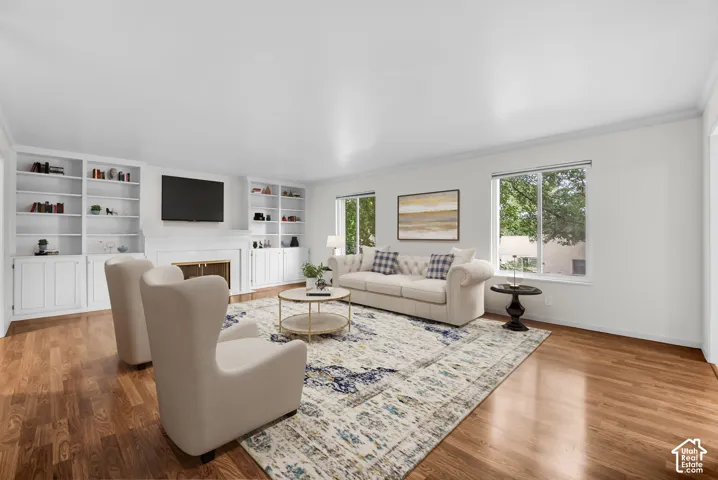 Hardwood flooring, recessed lighting, built-in shelving, fireplace with mantel, and multiple windows
