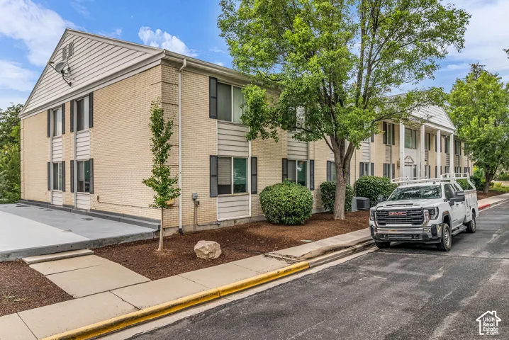 Two-story exterior with light brick and horizontal siding accents, featuring dark shutters and established landscaping