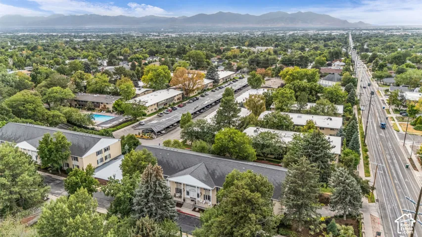 Expansive property featuring multiple residential buildings, a central swimming pool, covered parking structures, mature trees, and proximity to a major thoroughfare
