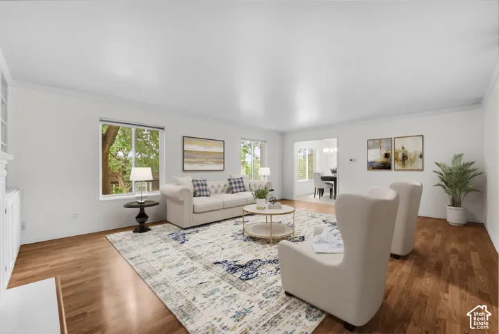 Bright living space featuring wood-finish flooring, crown molding, and multiple windows
