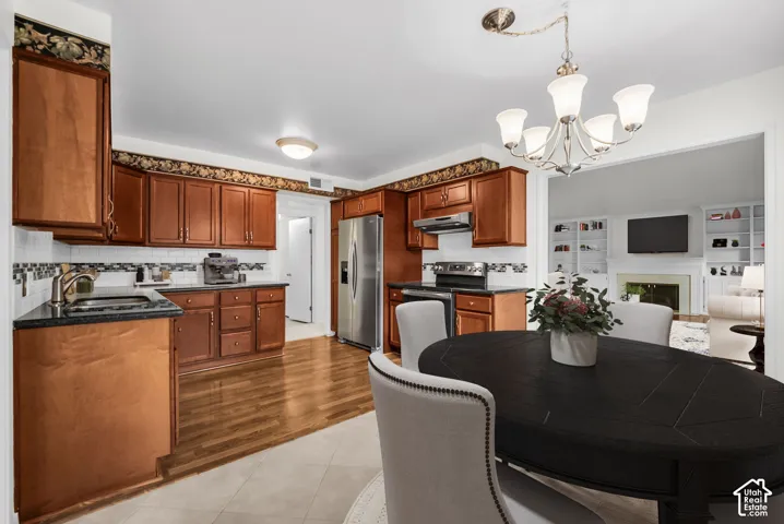 Kitchen featuring wood cabinetry, stainless steel appliances, dark countertops, and tile backsplash