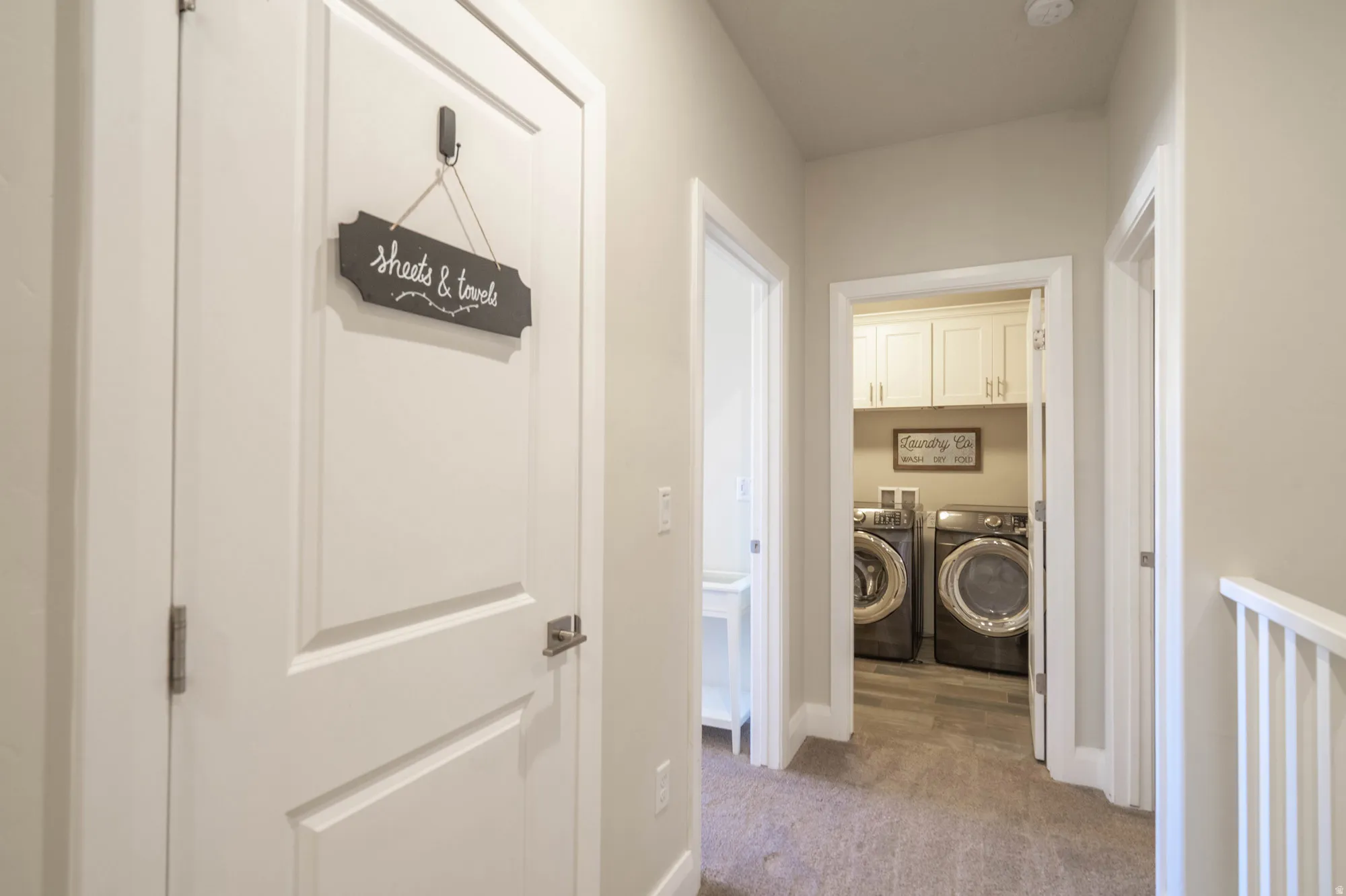 Dedicated laundry area with upper cabinetry and wood-finish flooring