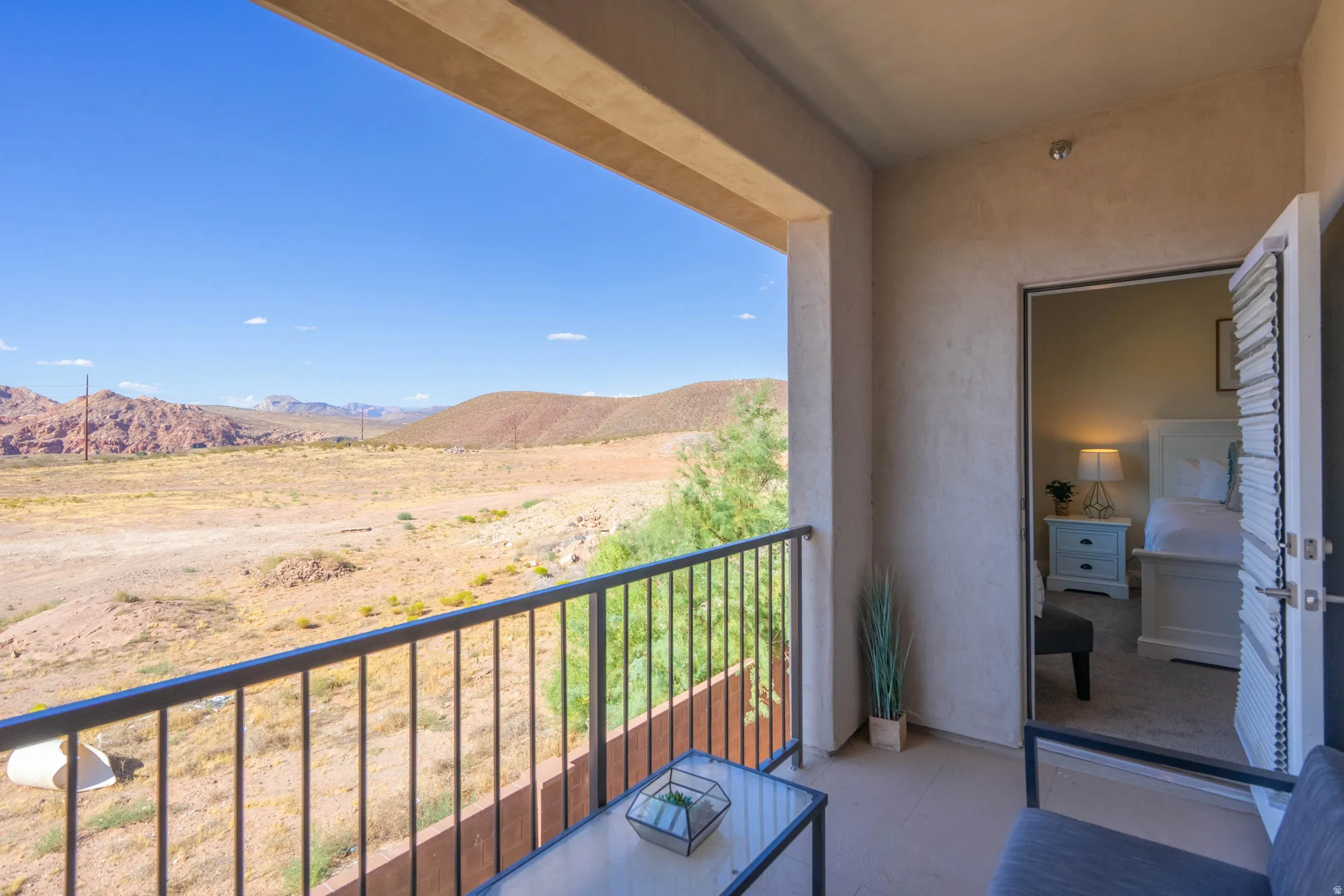 Outdoor balcony with wrought iron railing, concrete flooring, and direct access to an interior room