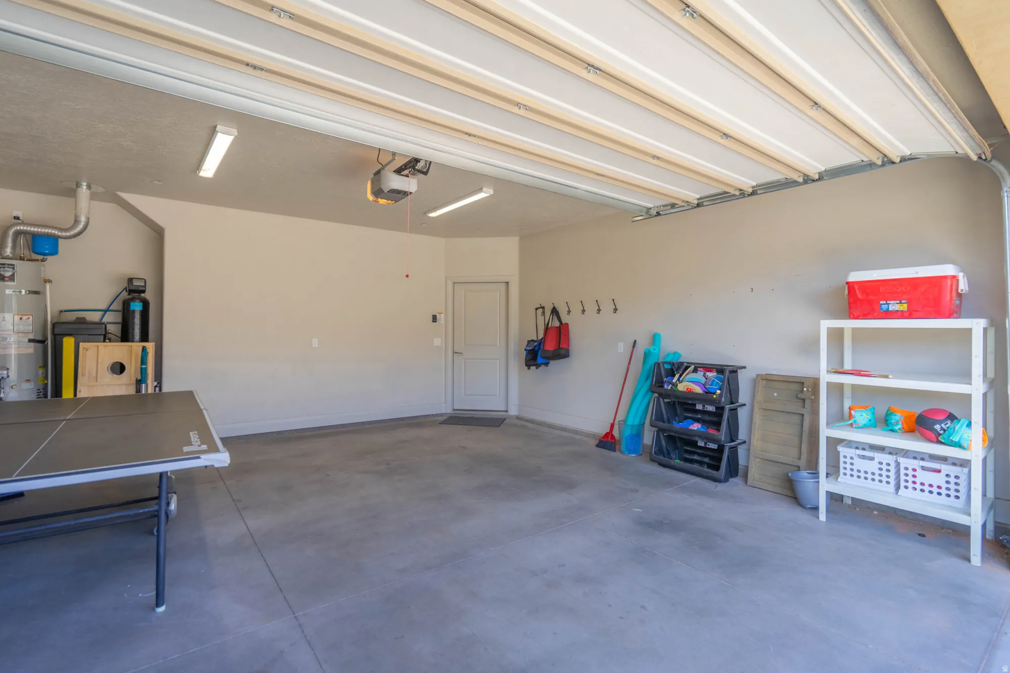 Spacious garage with a concrete floor, overhead lighting, and an accessible side entry door