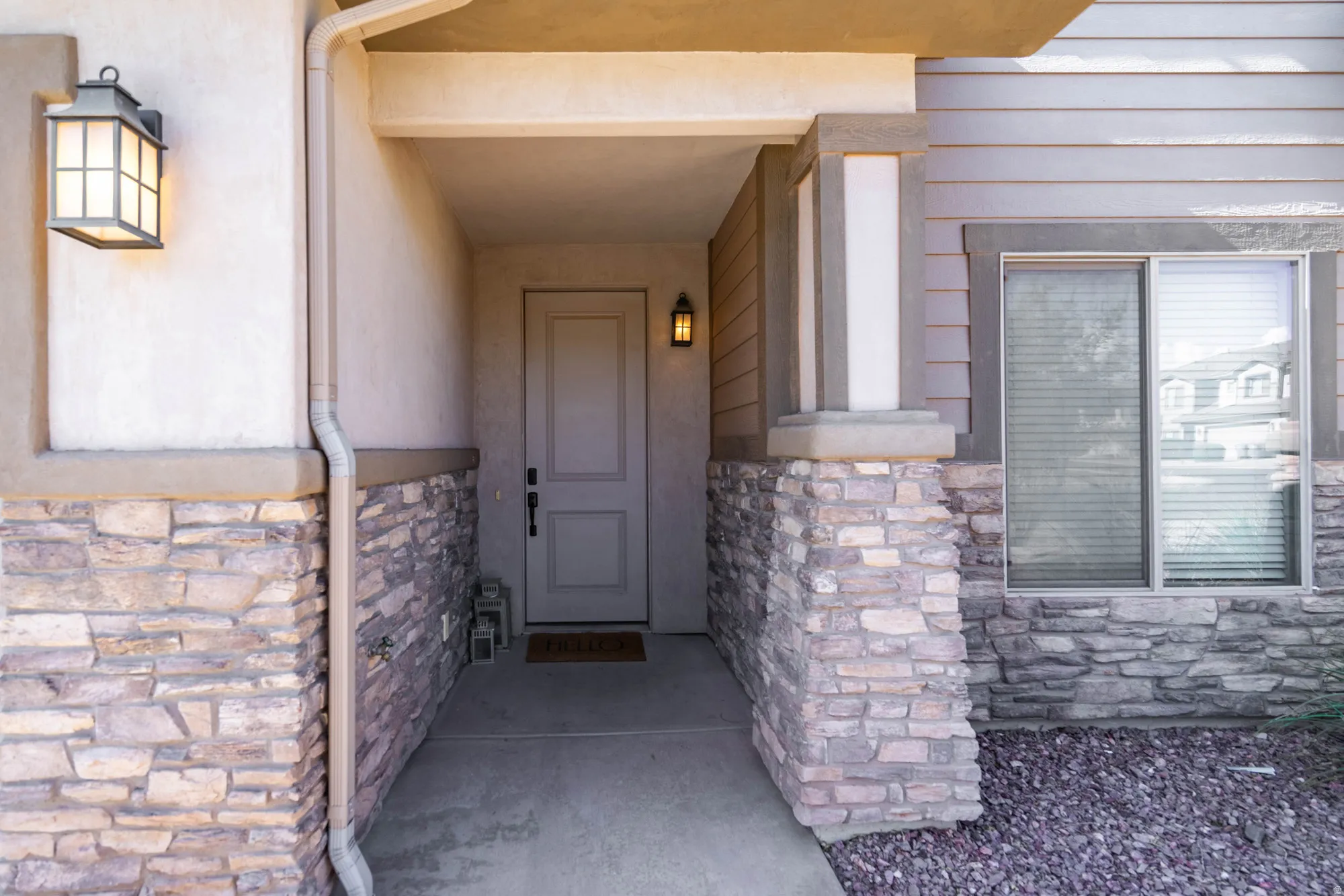 Covered entry featuring a paneled door, stone facade, and sconce lighting