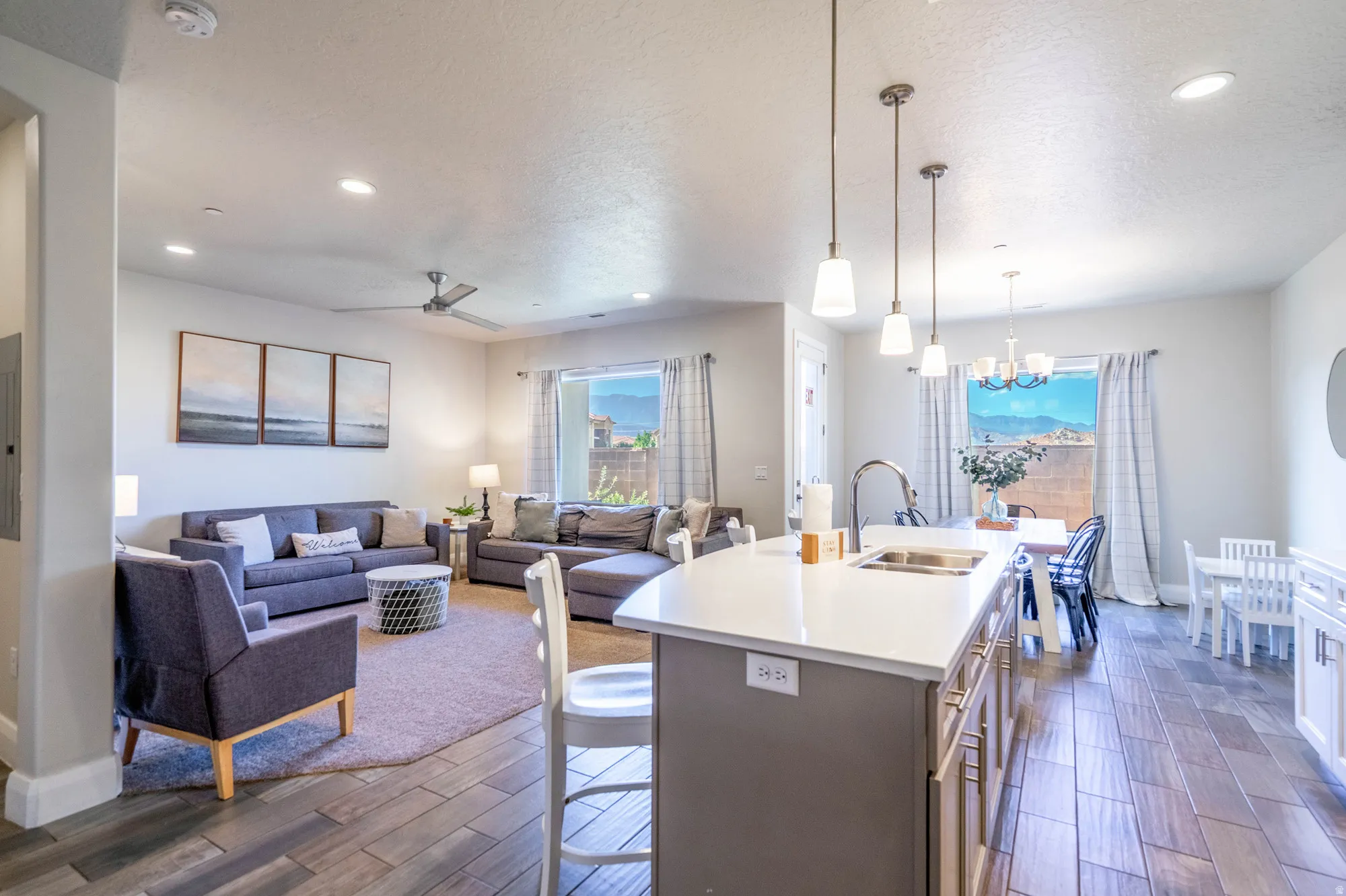 Open-concept living area featuring wood-finish flooring, a kitchen island with integrated sink, recessed lighting, and a ceiling fan