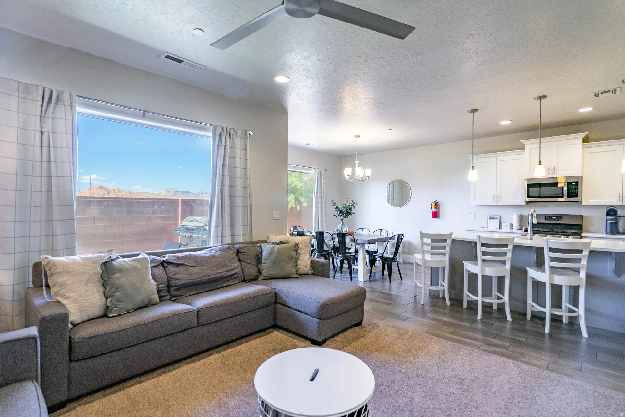Open-concept living space featuring a ceiling fan, recessed lighting, and a large window