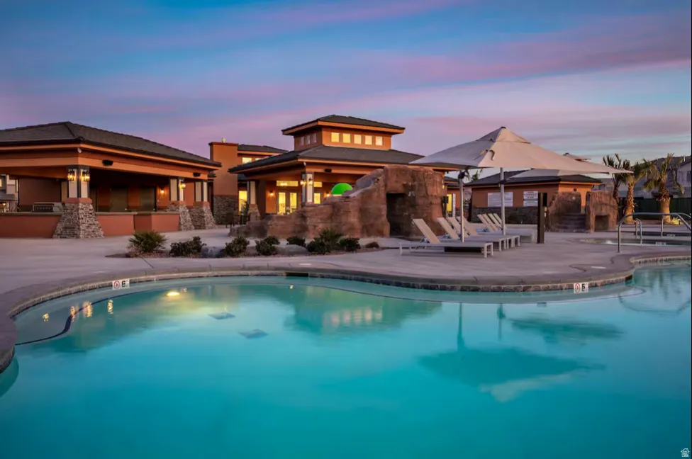 Resort-style pool with integrated rock features, a shade structure, and surrounding hardscaping