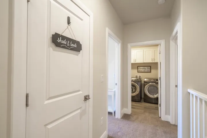 Dedicated laundry area with upper cabinetry and wood-finish flooring