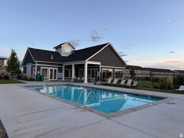 Outdoor swimming pool with concrete decking, surrounded by a dark-sided building featuring white columns and multiple windows