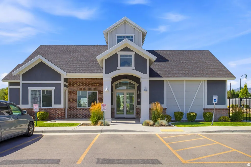 Exterior featuring a shingled roof, brick and siding facade, arched entryway, and a dormer