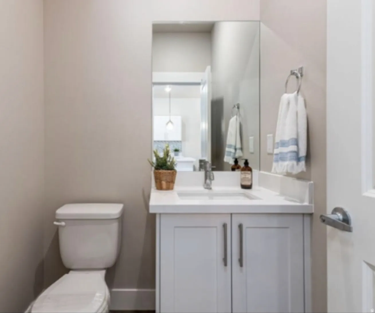White vanity with dual cabinet doors, chrome hardware, undermount sink, and a single-handle chrome faucet