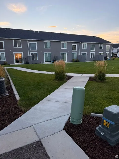 Expansive green space featuring a concrete pathway, mature landscaping, and multi-level residences with individual patios