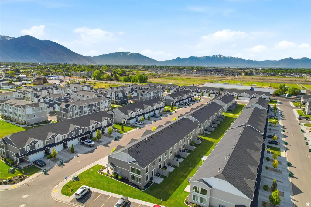 Mountain backdrop, residential community, multiple two-story townhomes, attached garages, manicured green spaces