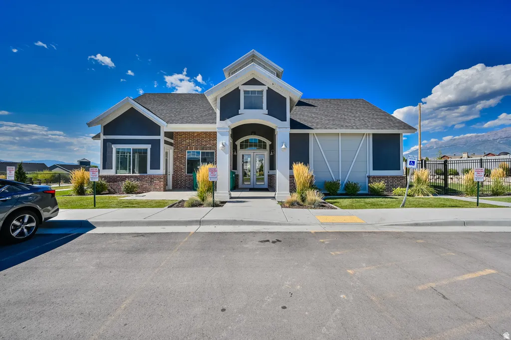 Exterior featuring a covered entry, dark siding, brick accents, and a shingle roof