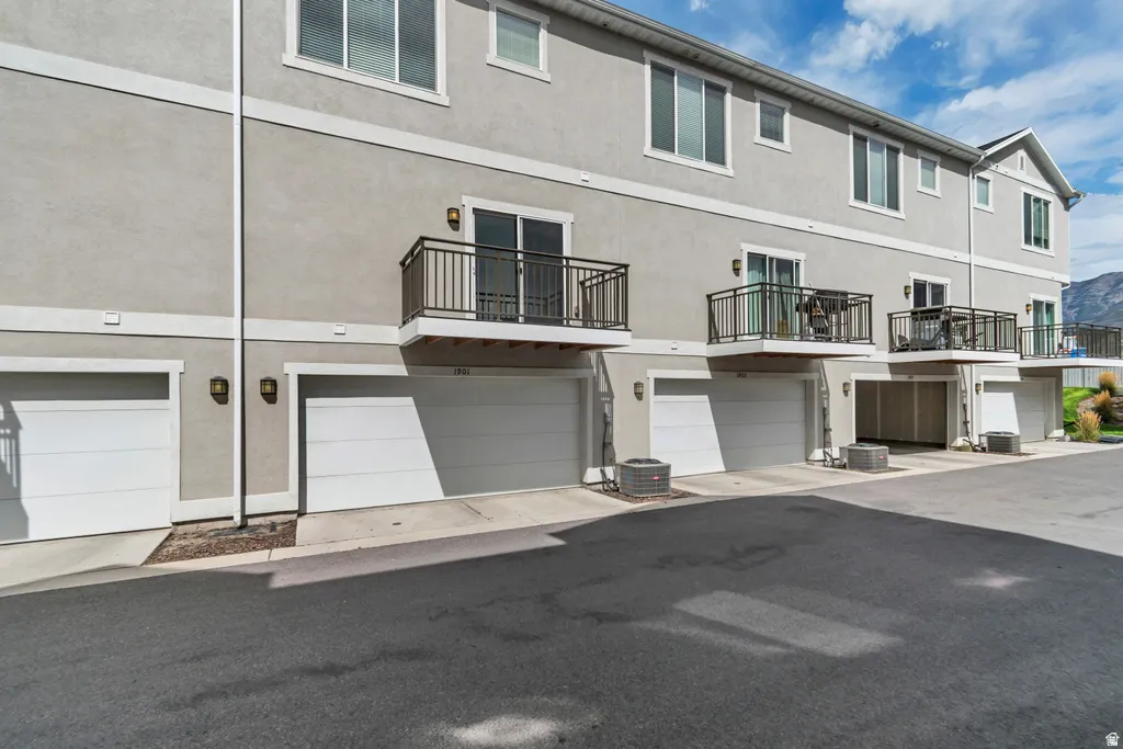 Stucco exterior with multiple private balconies, individual garages, and mountain backdrop