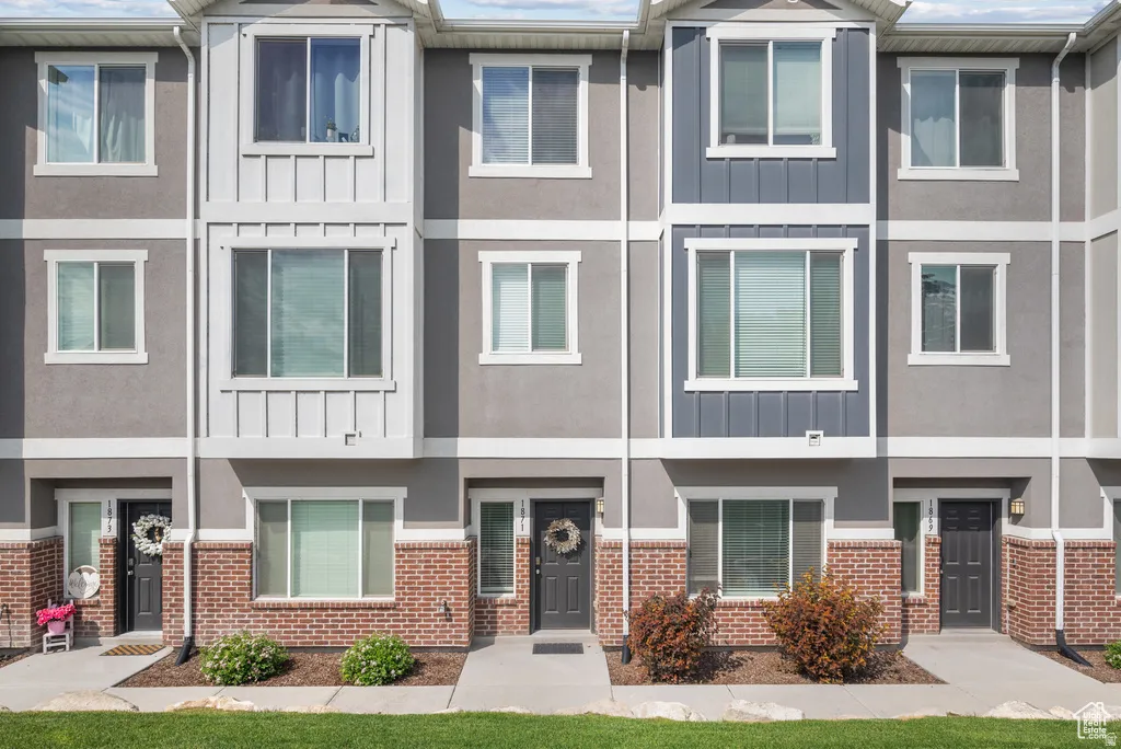 Multi-story townhome exterior featuring contemporary siding, brick detailing, and multiple windows