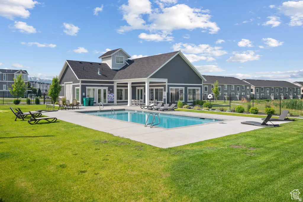 Community building with a swimming pool, concrete pool deck, and surrounding lawn