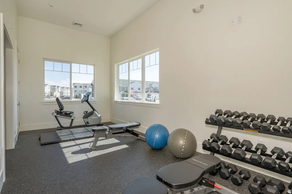 Vaulted ceiling, multiple windows, rubber flooring, and white walls