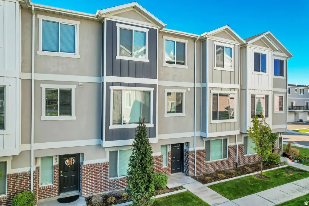 Modern multi-story townhouse with varied siding, a brick façade accent, and multiple windows