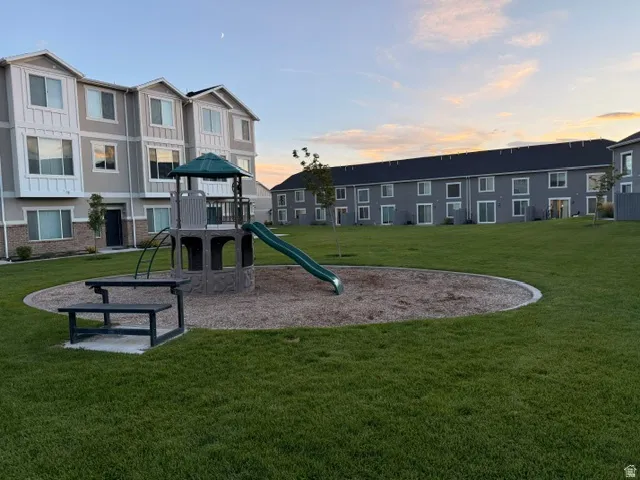 Expansive green space featuring a play structure with a slide, a picnic table, and manicured lawn areas