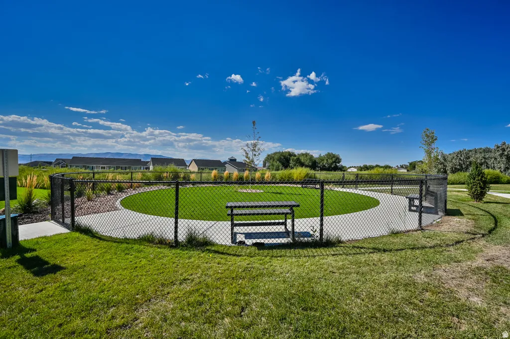 Fenced recreational area featuring a circular concrete path, artificial turf, and a built-in bench