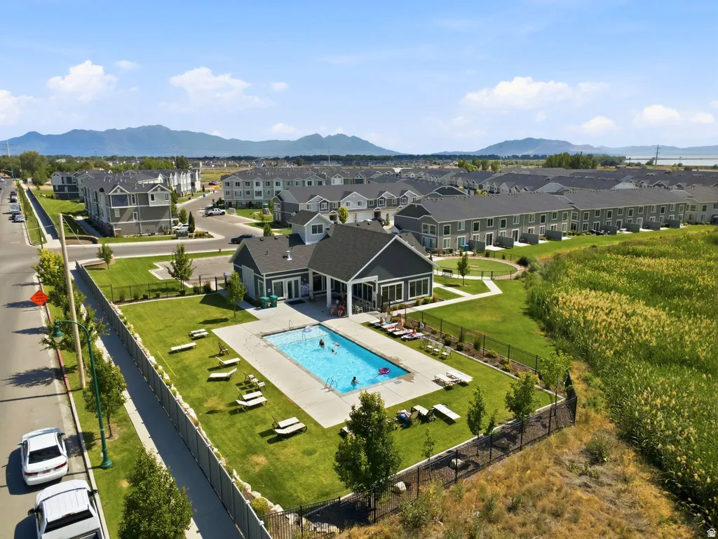 Outdoor swimming pool with a surrounding patio, adjacent lawn space, and a community building featuring a covered outdoor area