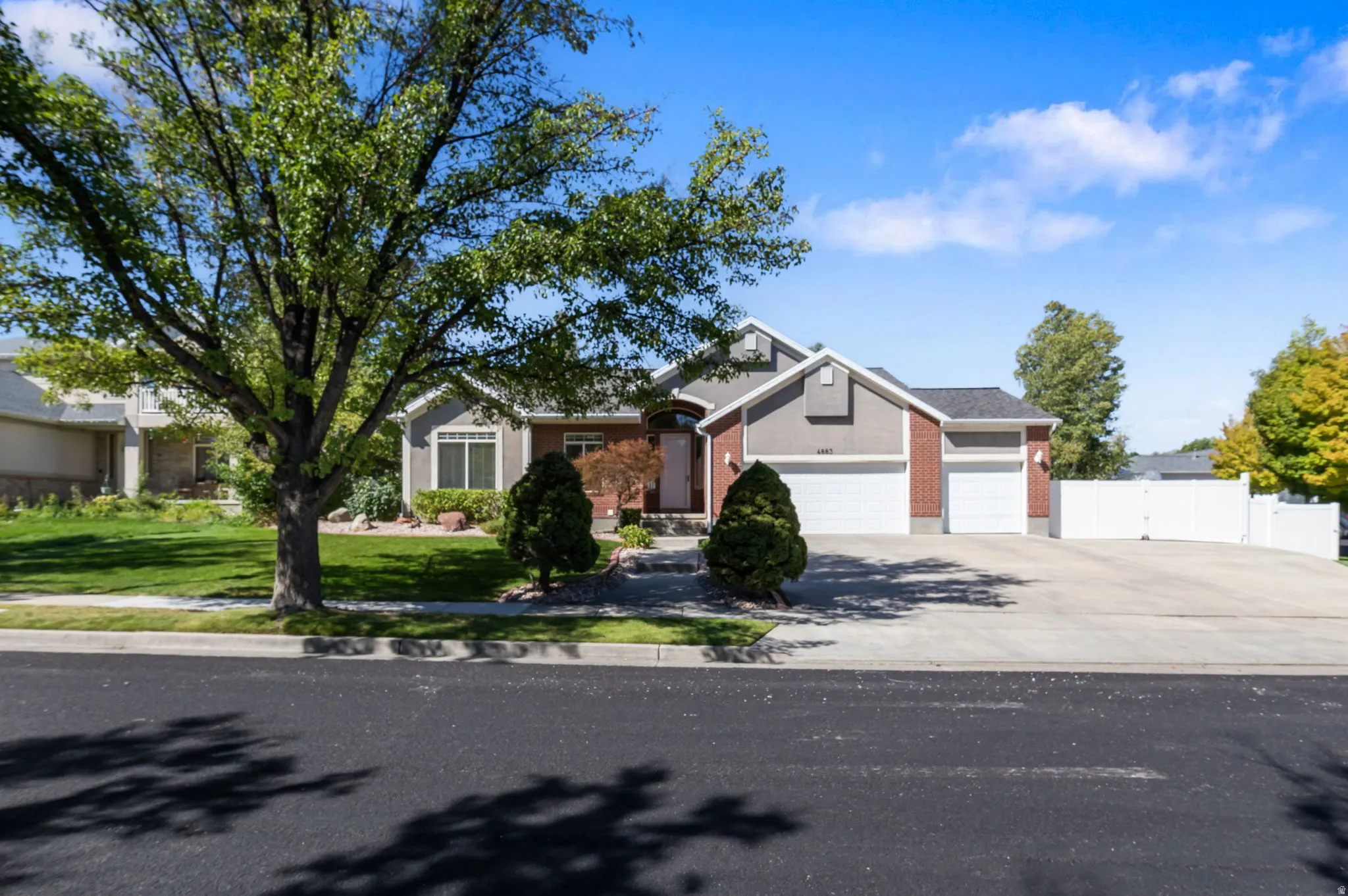Ranch-style exterior with brick and siding facade, attached two-car garage, mature landscaping, and an expansive concrete driveway