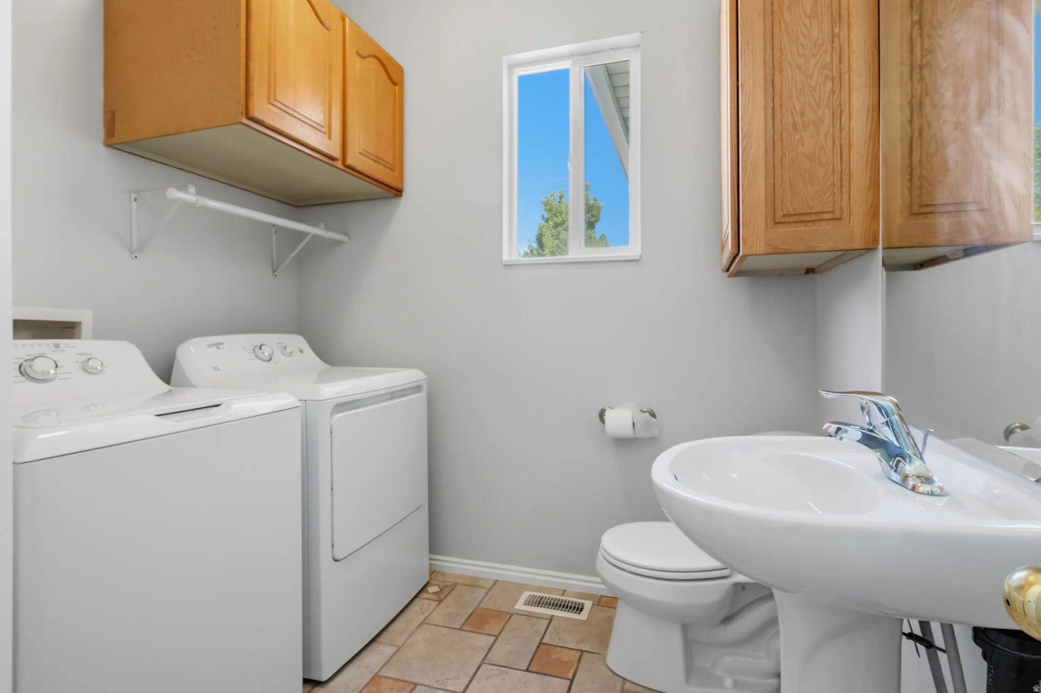 Ceramic tile flooring, pedestal sink, and overhead cabinetry