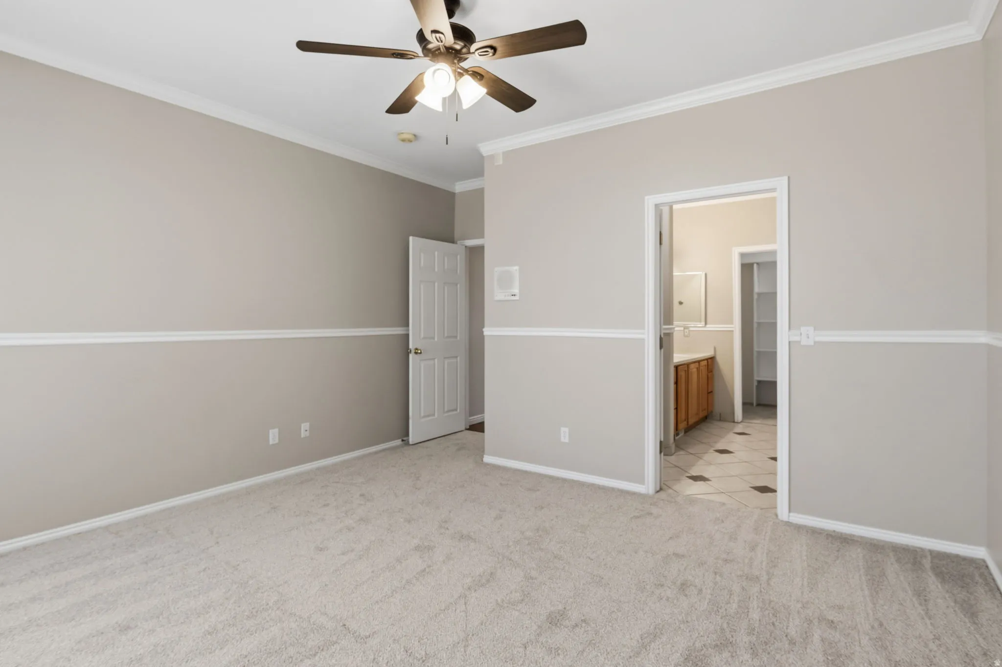 Carpeted room featuring crown molding, chair rail molding, and a ceiling fan with integrated lighting