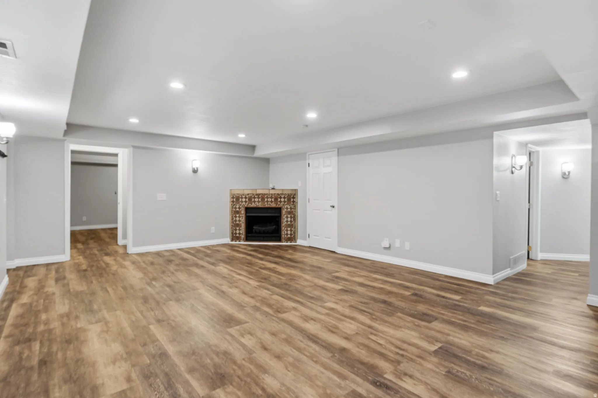 Spacious room featuring wood-finish flooring, recessed lighting, and a tiled fireplace