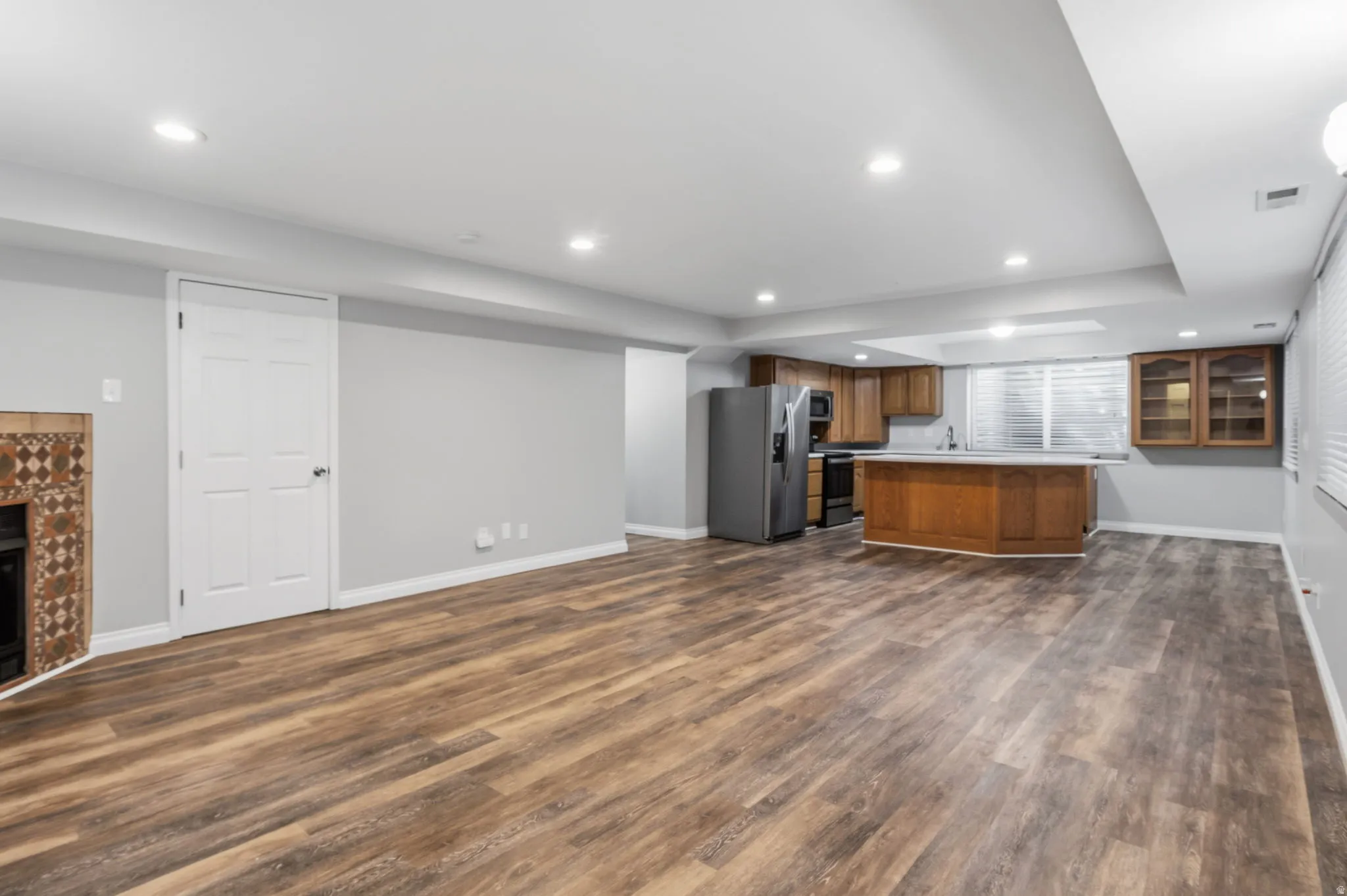Spacious open-concept area featuring wood-finish flooring, recessed lighting, and light gray walls