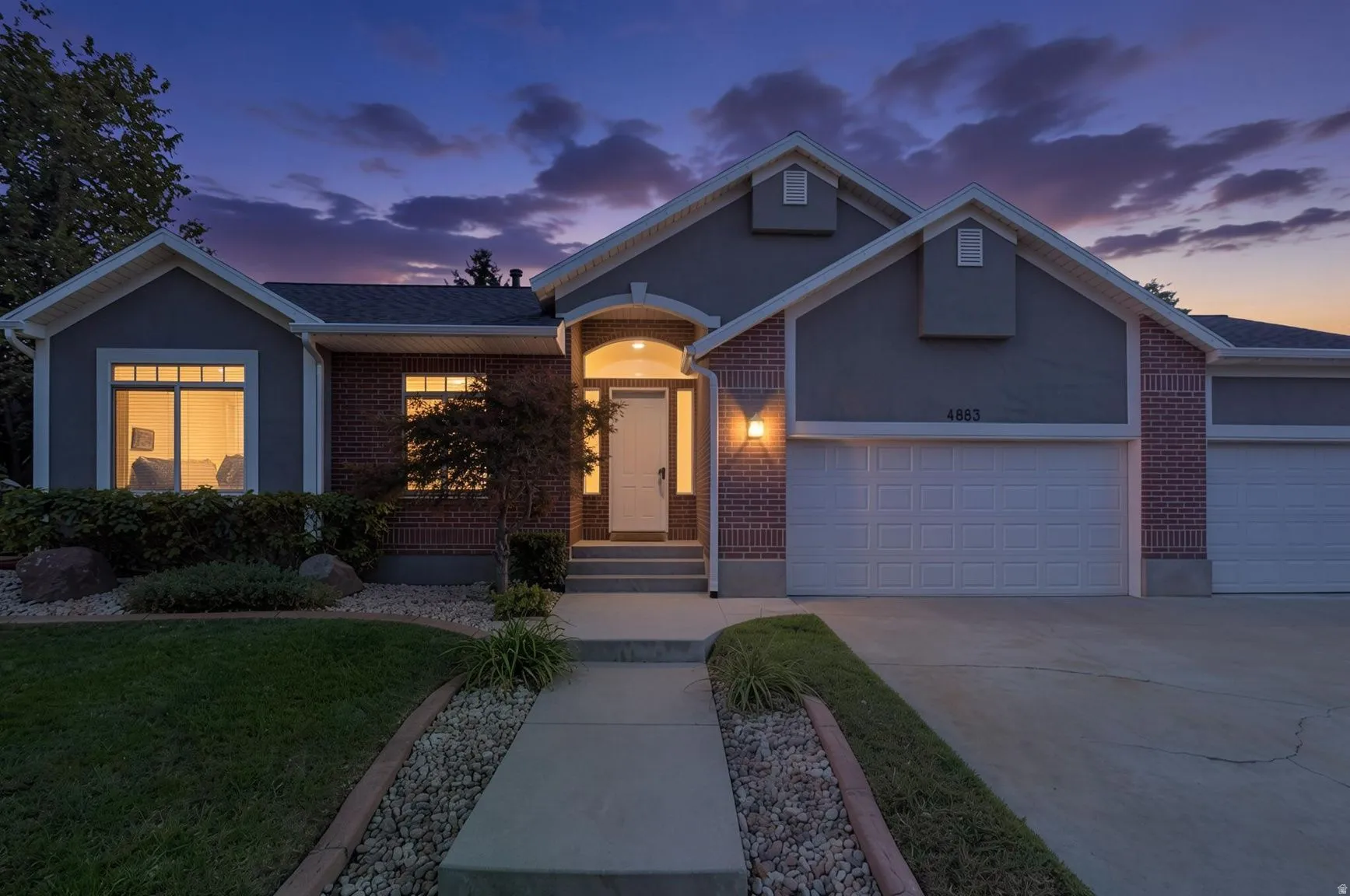 Brick and stucco exterior with multiple gables, arched entry, two-car garage, and established landscaping