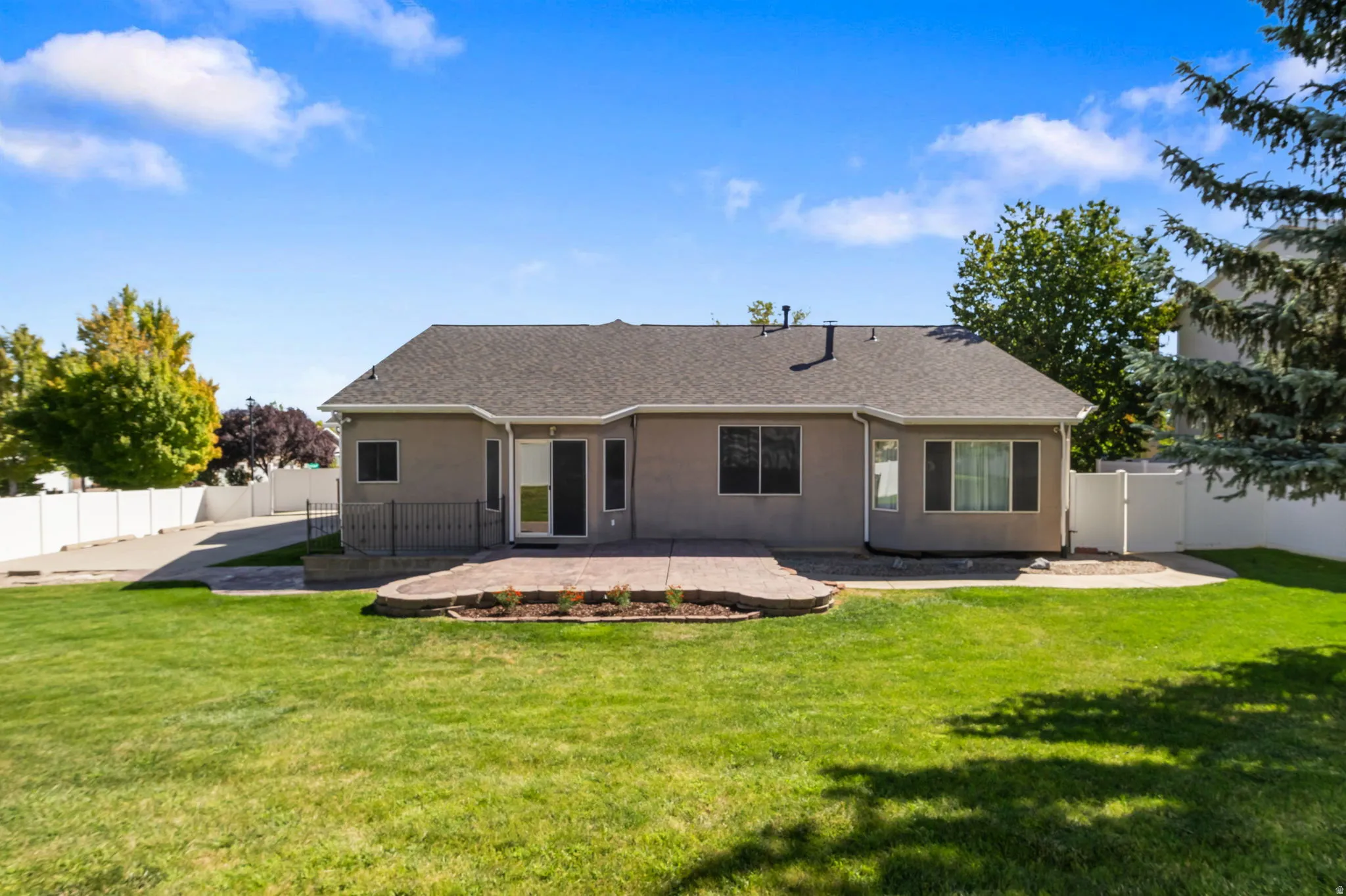 Expansive backyard featuring a large grass lawn, a stamped concrete patio, and a privacy fence