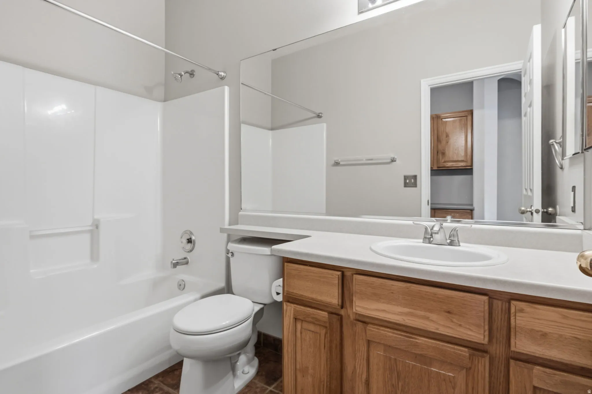 Bathroom featuring a built-in tub and shower combination, a vanity with a light-toned countertop, and wood-finish cabinetry
