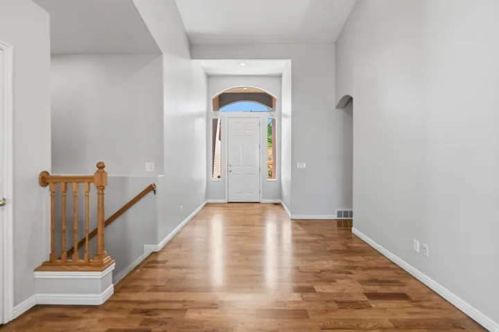 Wood-finish flooring, arched entryway, staircase with wood banister, and recessed archway