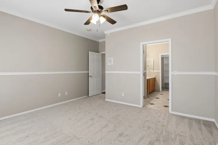 Carpeted room featuring crown molding, chair rail molding, and a ceiling fan with integrated lighting