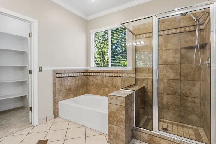 Tiled shower enclosure with glass surround, built-in bench, and handheld shower fixture
