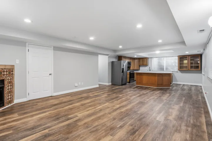 Spacious open-concept area featuring wood-finish flooring, recessed lighting, and light gray walls