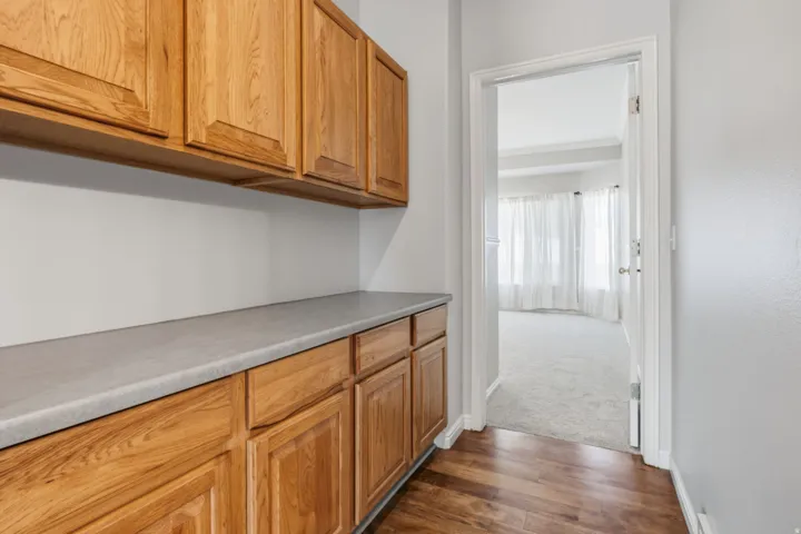 Wood-finish flooring, extensive cabinetry with upper and lower storage, and a durable countertop