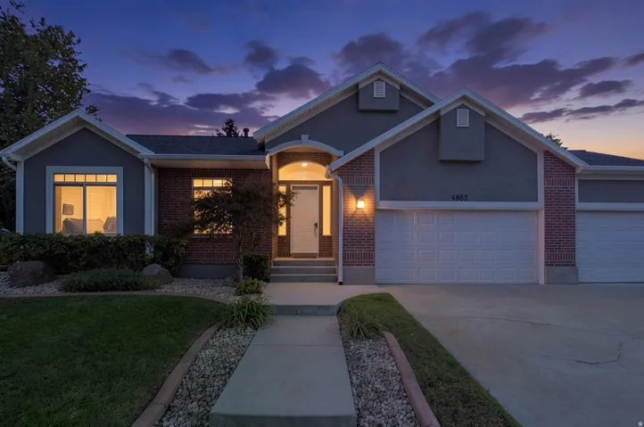 Brick and stucco exterior with multiple gables, arched entry, two-car garage, and established landscaping